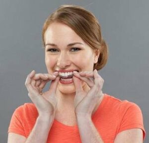 Happy Invisalign patient putting on her clear aligners in Chattanooga