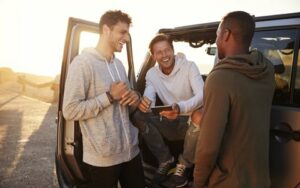 Several young men talking outside of a vehicle happy to have toothache relief from root canal treatment