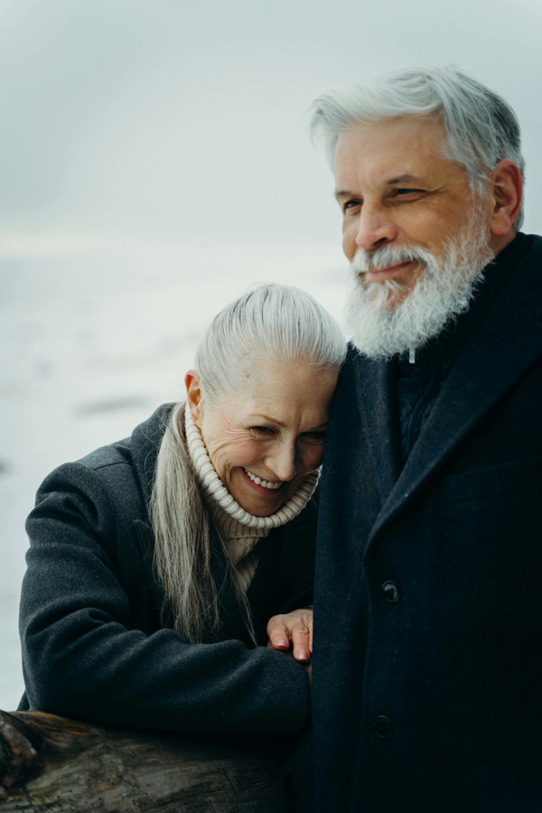 Smiling older couple holds back laughter outdoors